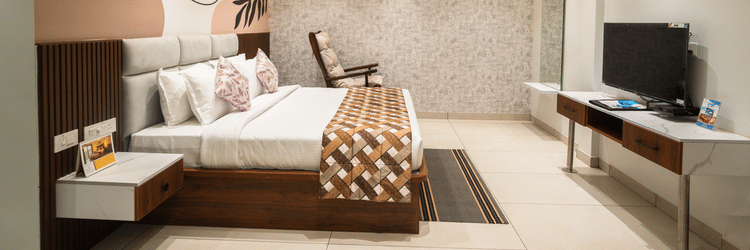 An image of a hotel bedroom with a large bed placed in front of a wall-mounted television - MGM Whispering Meadows