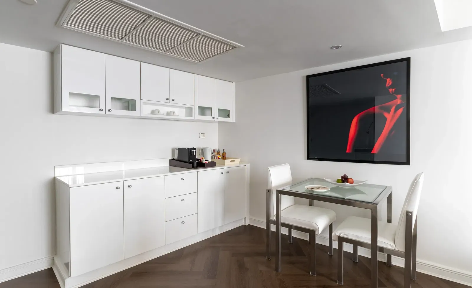 Kitchenette with white cabinets, breakfast bar, and abstract artwork at Night Hotel Bangkok.