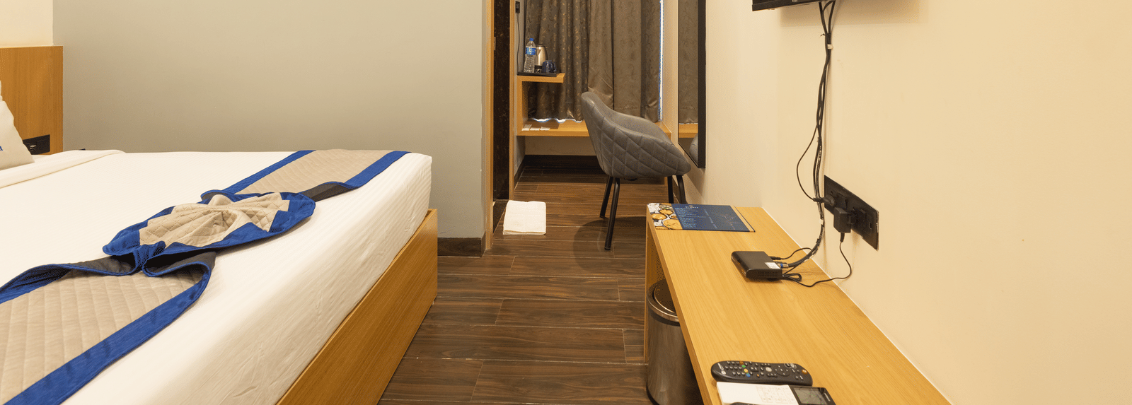 Interior view of a guest room showing the bed, television, and small desk area at Pravasa Stay Luv Kush, Indore.