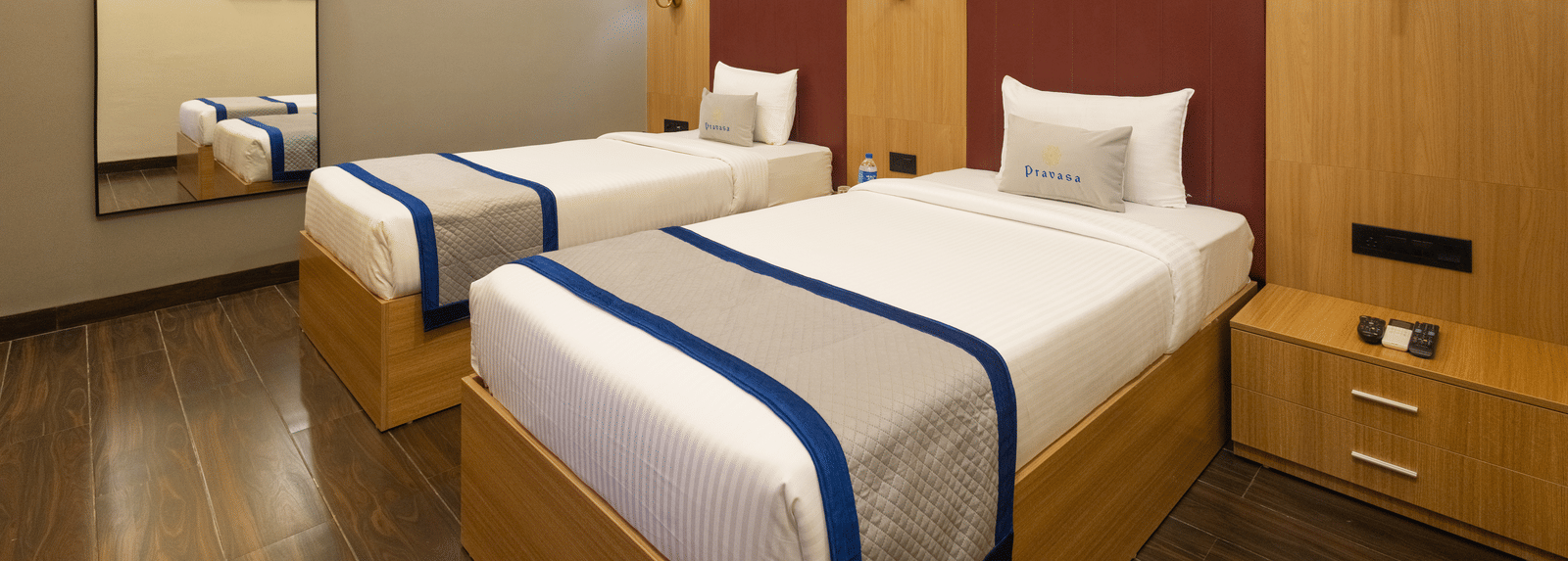 Interior view of a guest room showing 2 single beds and a mirror at Pravasa Stay Luv Kush, Indore.