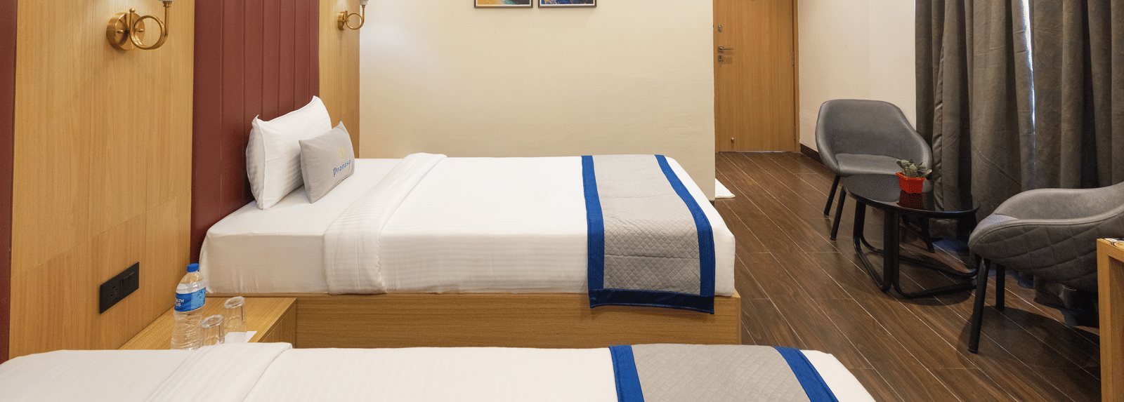 Interior view of a guest room with 2 single beds and seating at Pravasa Stay Luv Kush, Indore.