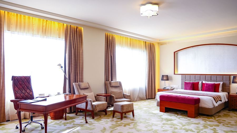 A luxurious bedroom with a king size bed, a work desk, and comfortable seating, bathed in natural light - Balaji Sarovar Premiere, Solapur