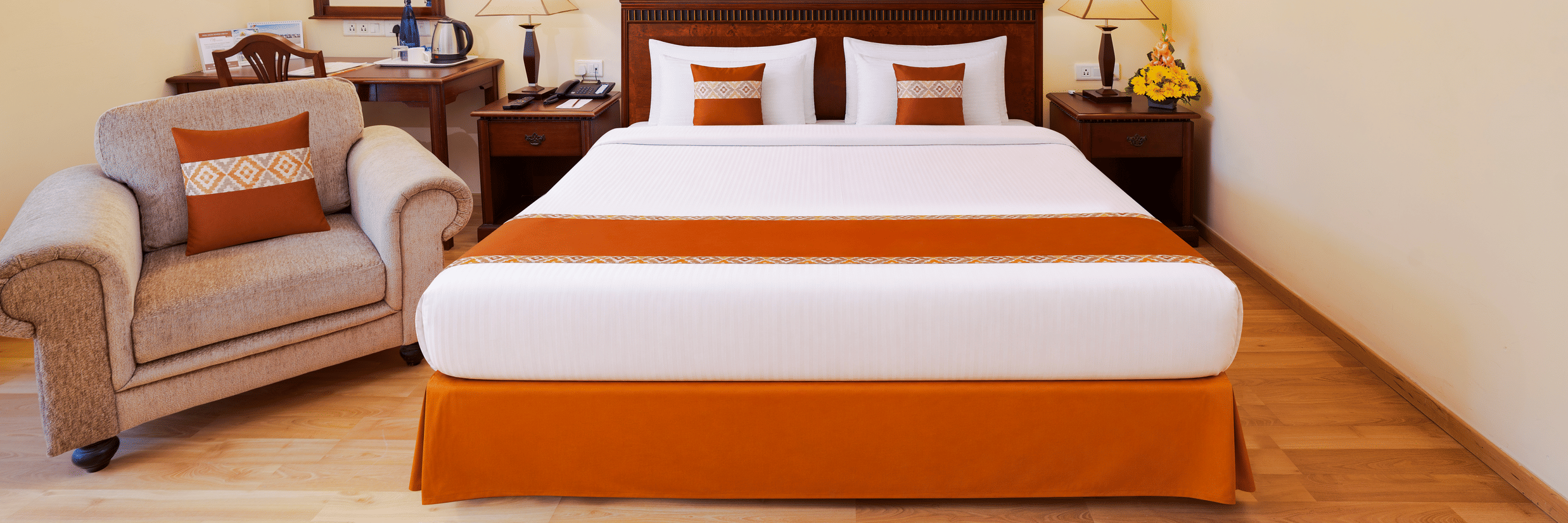 A room with a large bed, spreads, pillows, a sofa, a mirror, and lights. | MGM Mark Whitefield