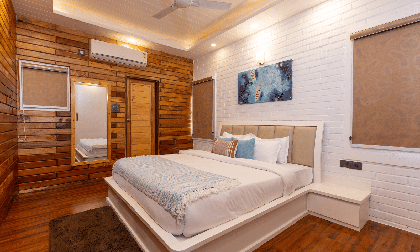 A contemporary hotel bedroom with a large white bed, wooden walls, and dark flooring at Megha Resort & Villas, Dehradun.