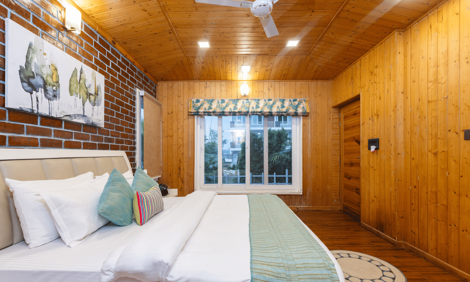 A comfortable, modern bedroom with wood-panelled walls, a large bed, and a simple, decor - Megha Resort & Villas, Dehradun