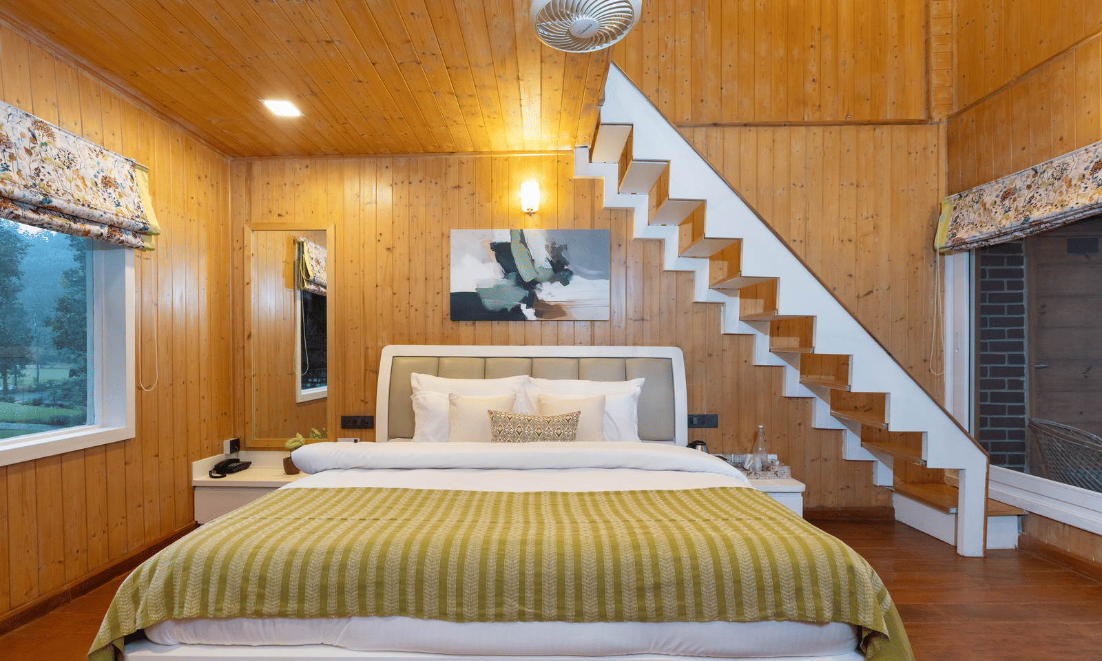 A double bed and a modern, white open staircase dominate the warm, wood-panelled bedroom interior - Megha Resort & Villas, Dehradun