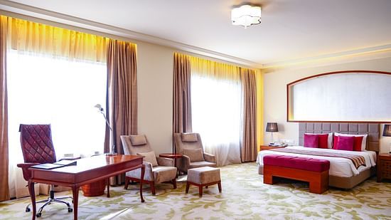 A luxurious bedroom with a king size bed, a work desk, and comfortable seating, bathed in natural light - Balaji Sarovar Premiere, Solapur