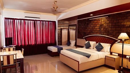 full view image of the deluxe room featuring a double bed along with a dining area right opposite the bed at The Grand Krishna Rooms in Bengaluru