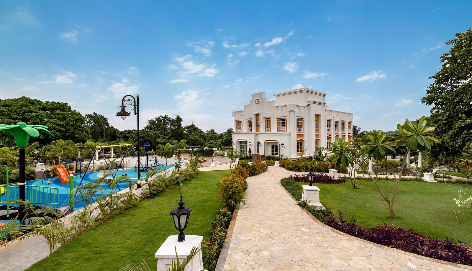 An outdoor play area for kids along side a pathway leading to the facade of Imperial Goa.