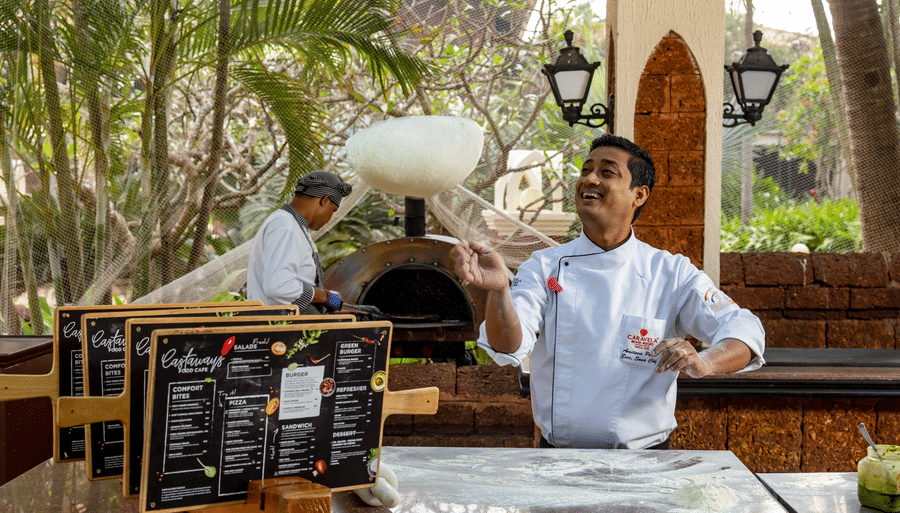 a chef throwing a pizza dough - Caravela Beach Resort Goa