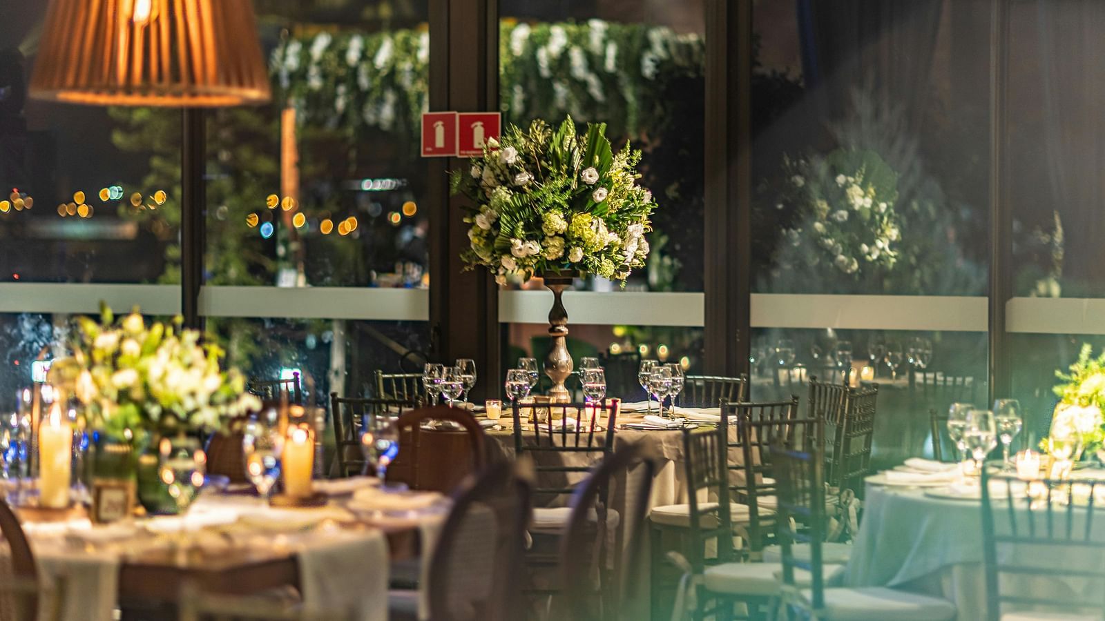 An overview of a beautiful banquet hall with tables decorated with shiny glassware and flowers.