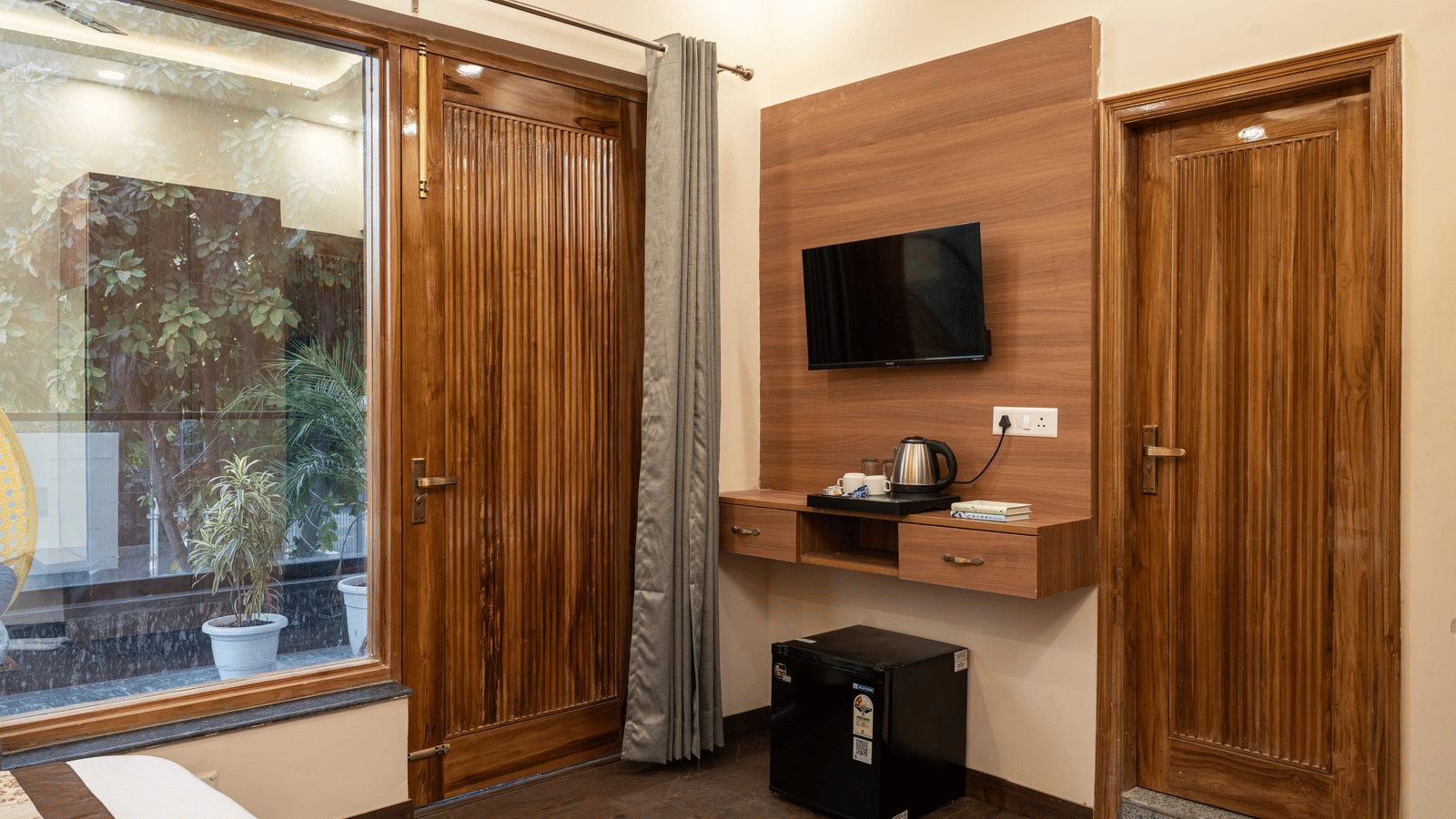 Contemporary hotel room with a television, wardrobe, and work area.