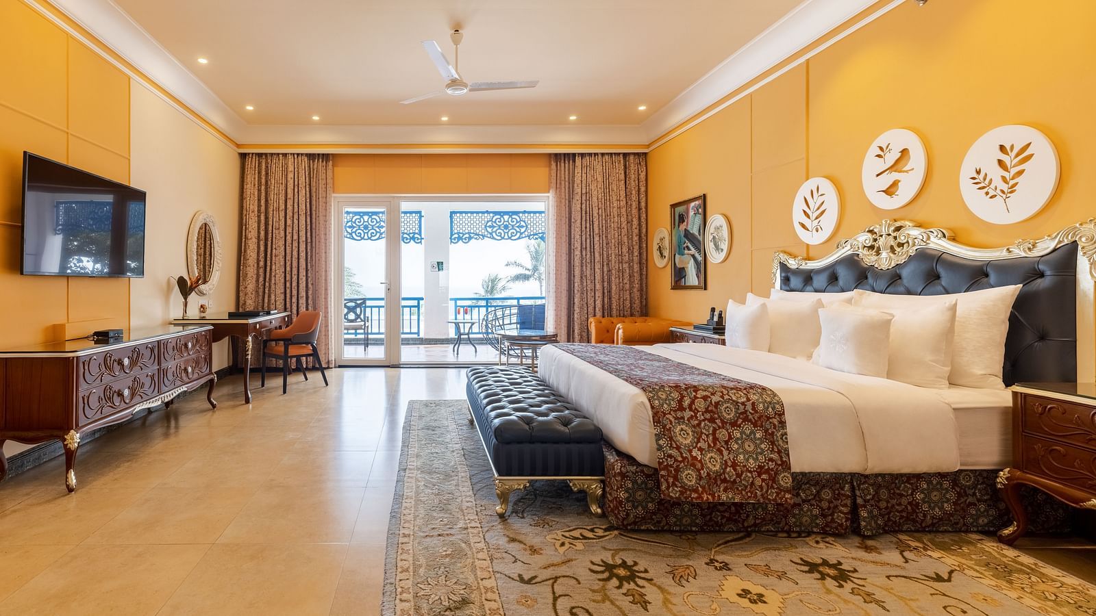 Spacious bedroom with wall-mounted TV, a workstation, and a seating area with large glass windows at MAYFAIR Palm Beach Resort, Gopalpur-On-Sea