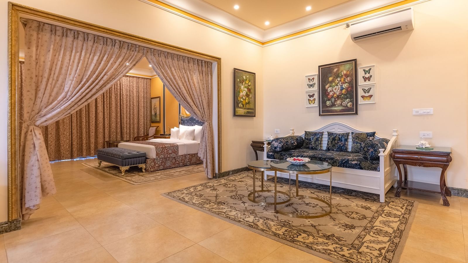 A double bedroom, with a separate living space with sofa and a coffee table and a wall-mounted air-conditioner at MAYFAIR Palm Beach Resort, Gopalpur-On-Sea