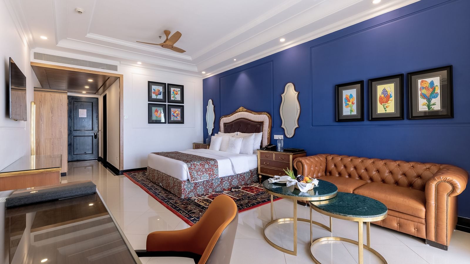 Double bed room with seating area, a workstation, a ceiling fan, and a wall-mounted TV at MAYFAIR Palm Beach Resort, Gopalpur-On-Sea