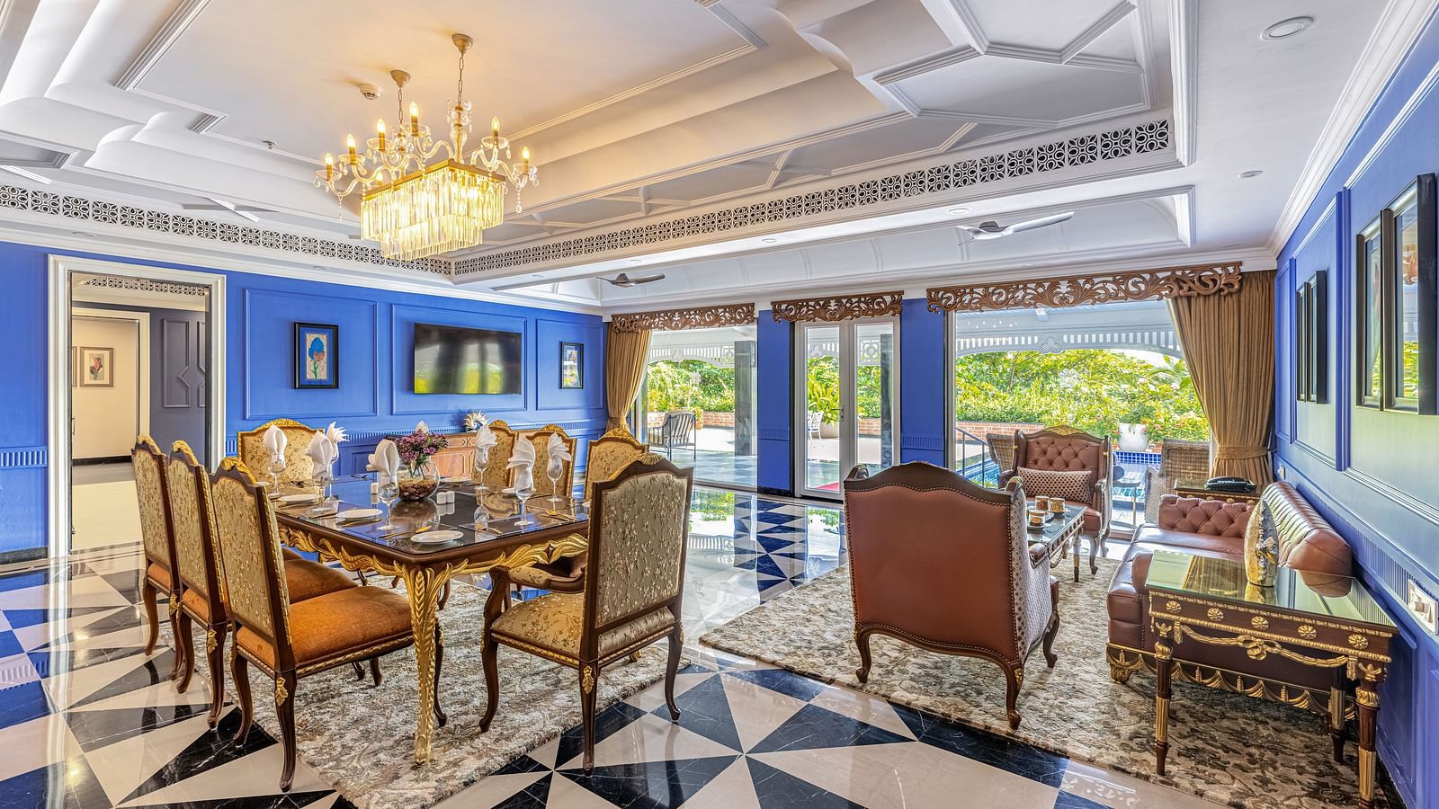 Luxurious dining and lounge area with royal blue walls, ornate chandelier, black-and-white checkered floor, and elegant furniture at MAYFAIR Palm Beach Resort, Gopalpur-On-Sea
