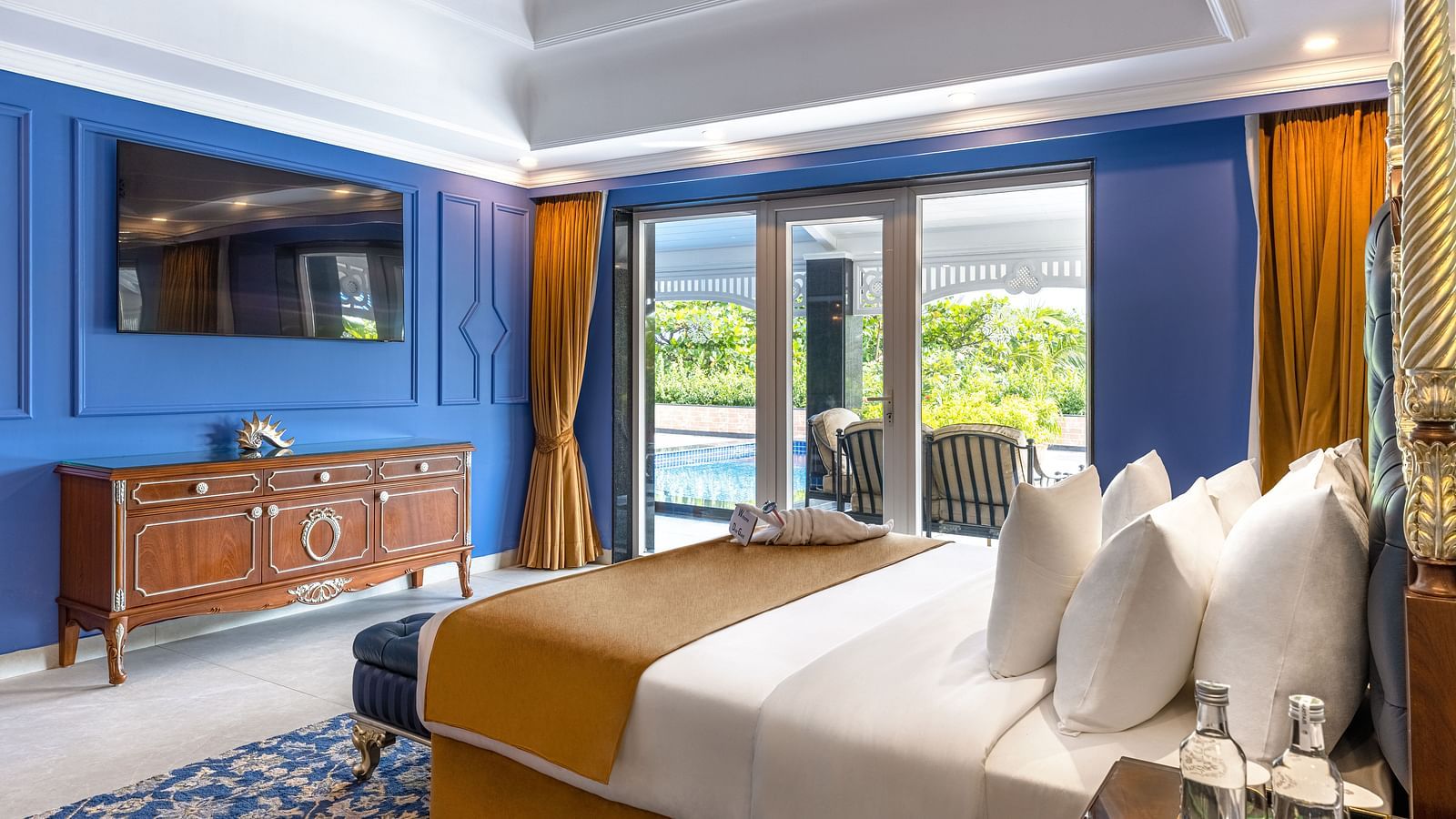 Luxury bedroom with blue accent wall and balcony view at MAYFAIR Palm Beach Resort, Gopalpur-on-Sea