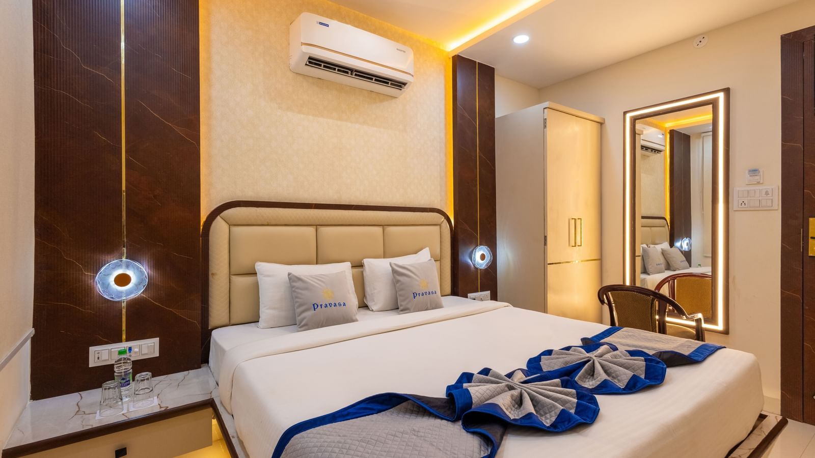 A well lit room with a double bed, side tables, mirror with a chair, and air conditioning at Pravasa Stay Dewas Naka, Indore.