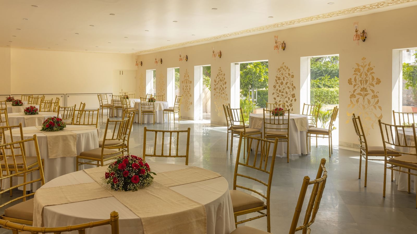 A banquet hall with multiple round tables and chairs, possibly at Royal Heritage Haveli, ready for an event.