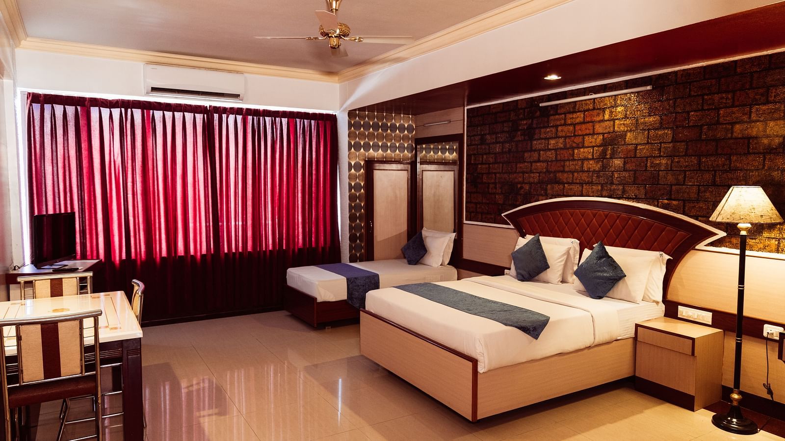 full view image of the deluxe room featuring a double bed along with a dining area right opposite the bed at The Grand Krishna Rooms in Bengaluru