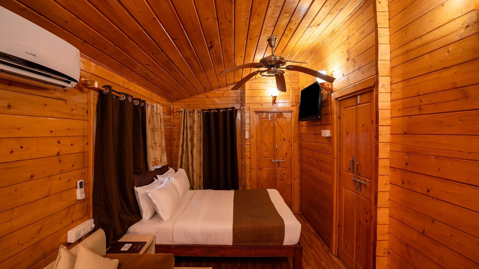 Image of orion suite with wooden furnishing featuring a king size bed and other amenities like couch and air conditioning | The Grand Legacy Resort and Spa