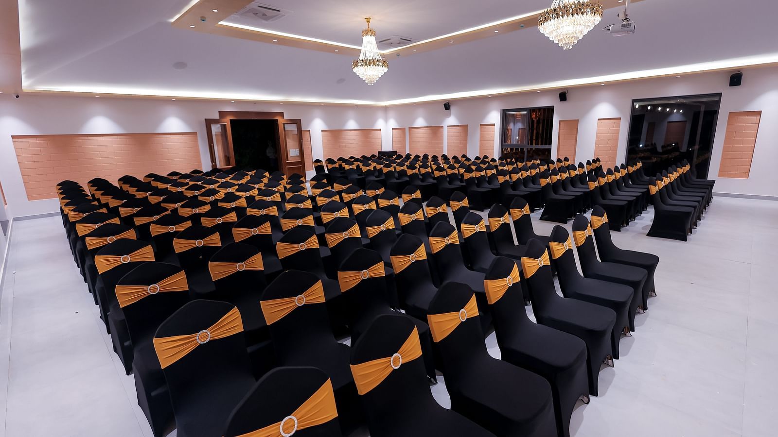 Conference hall at Trishvam Symphony, Krishnagiri, set up with rows of cushioned chairs for seminars or presentations.