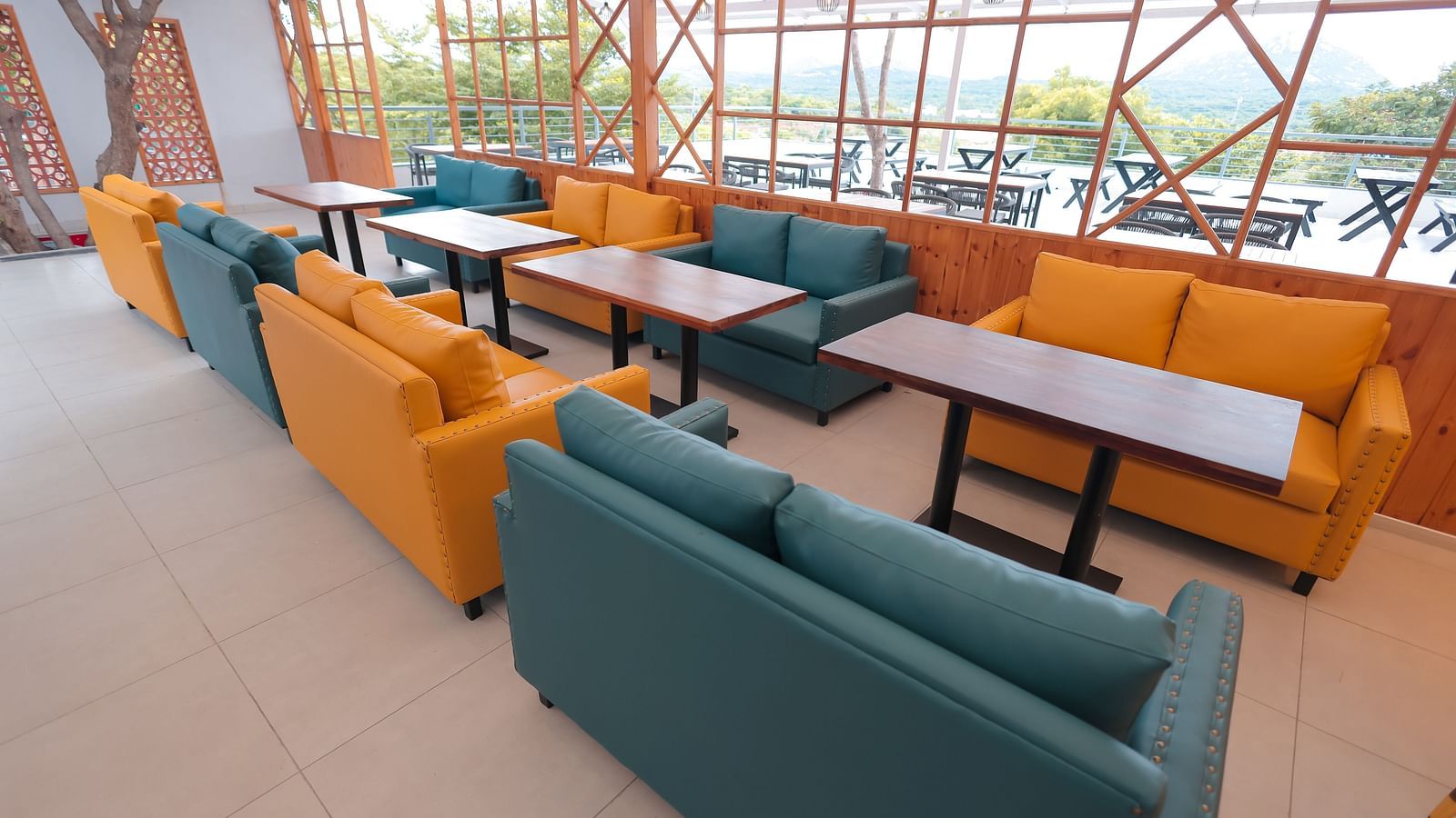 Contemporary lounge area at Trishvam Symphony, Krishnagiri, with colourful couches and ample seating for casual gatherings.