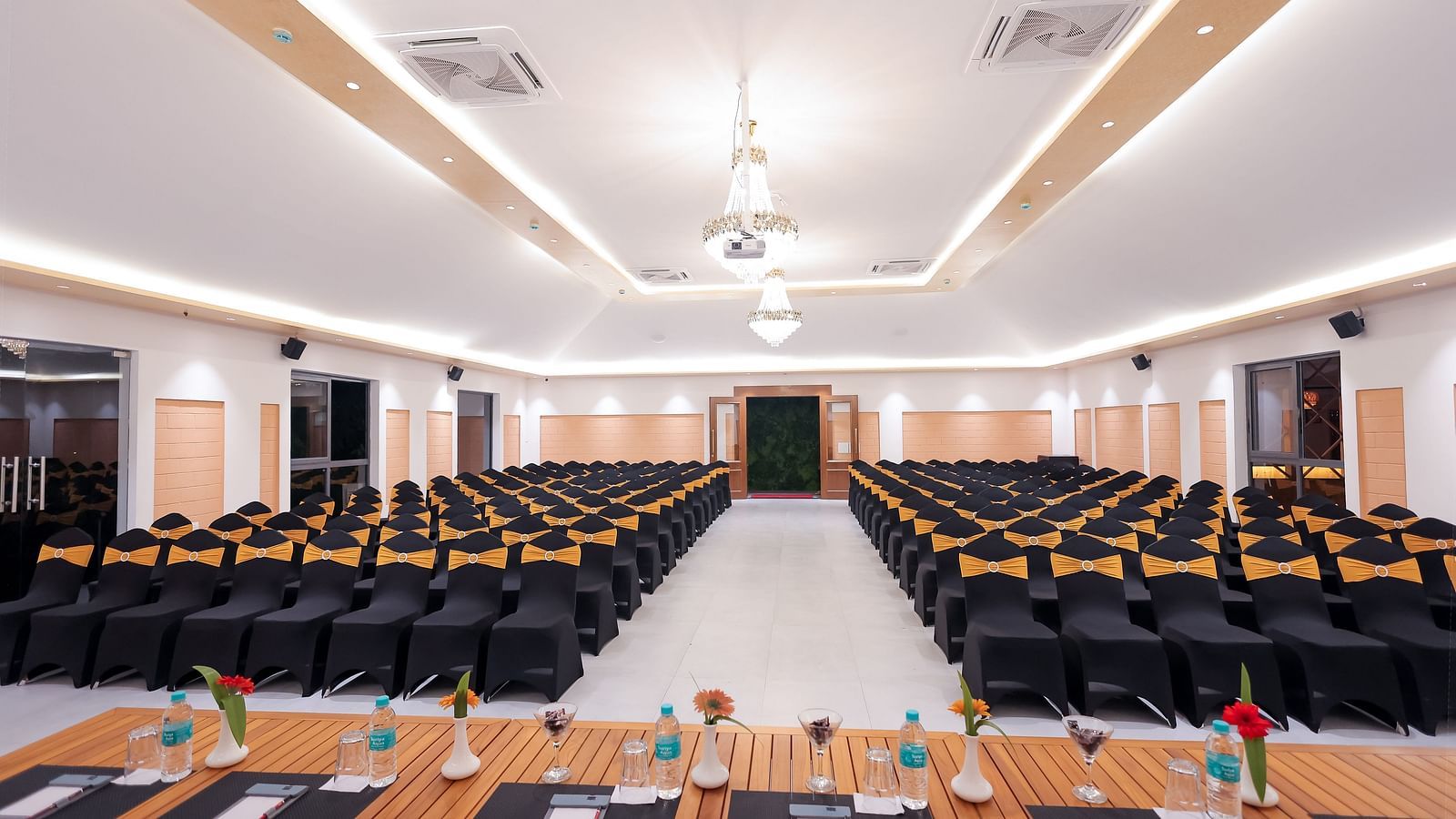 Modern indoor conference hall setup at Trishvam Symphony, Krishnagiri, featuring classroom-style seating and AV equipment.
