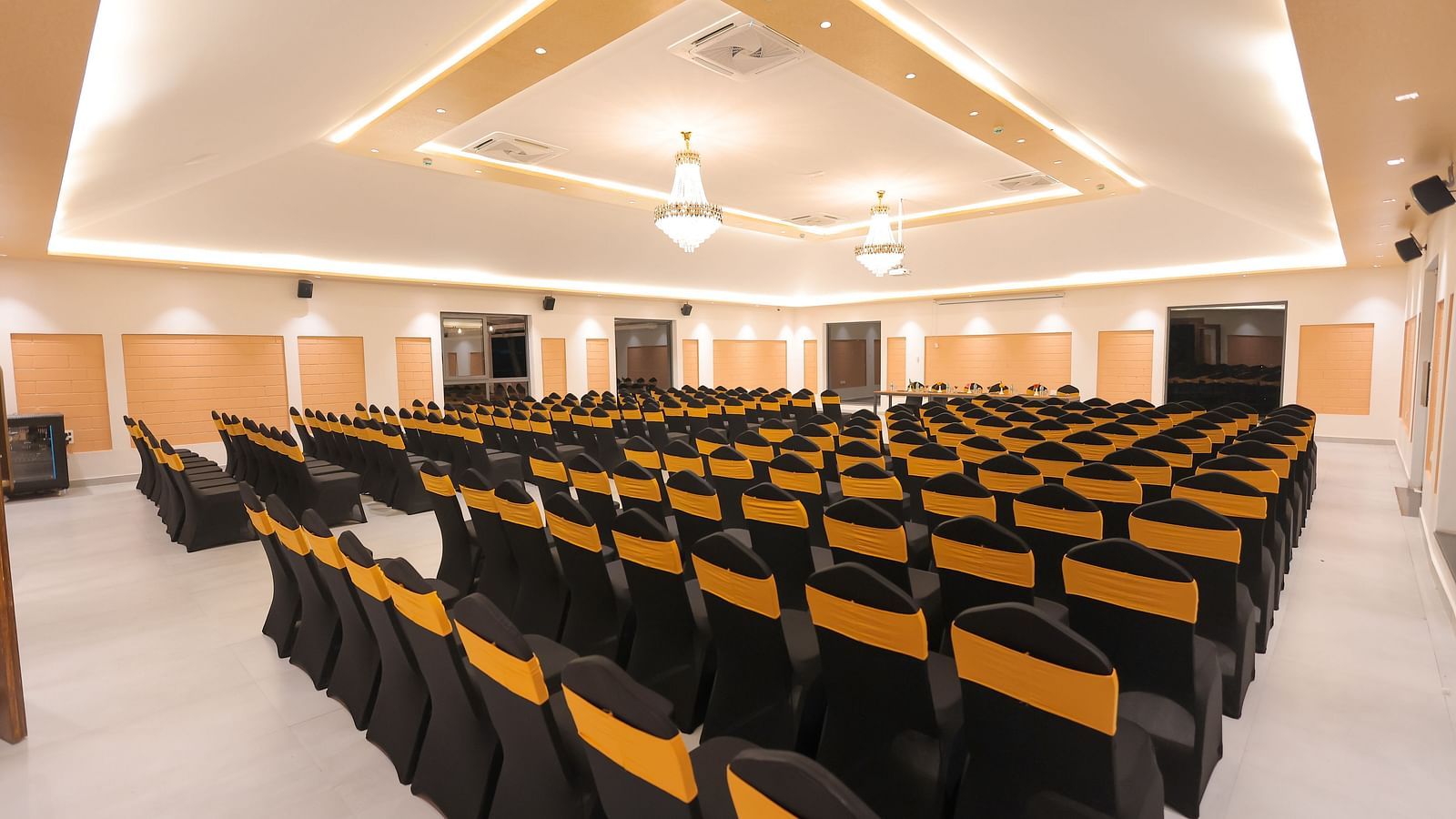 Spacious seminar hall at Trishvam Symphony, Krishnagiri, with black and yellow cushioned chairs arranged theatre-style.