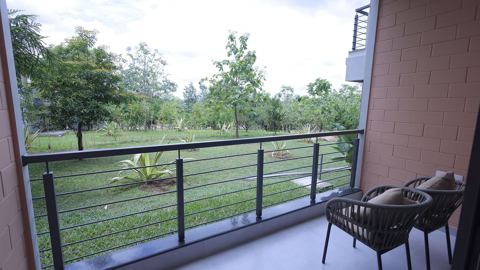 Balcony view with two chairs overlooking lush greenery at Trishvam Symphony, Krishnagiri.