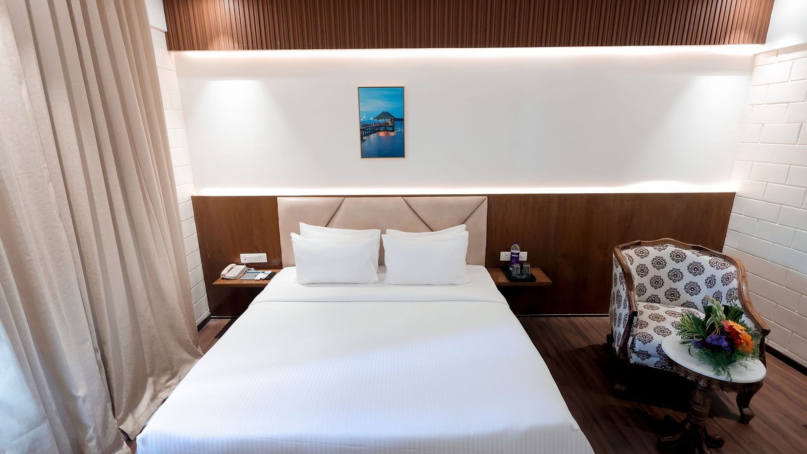 Double bed with white bedding and floral arrangements in cosy room at Trishvam Symphony, Krishnagiri.