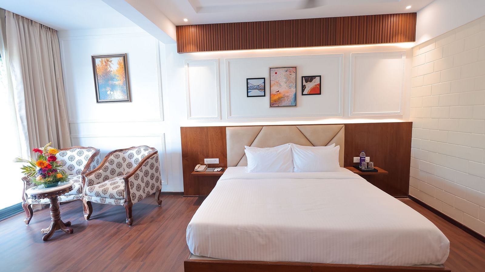 Neatly arranged bedroom with twin chairs and wall art at Trishvam Symphony, Krishnagiri.