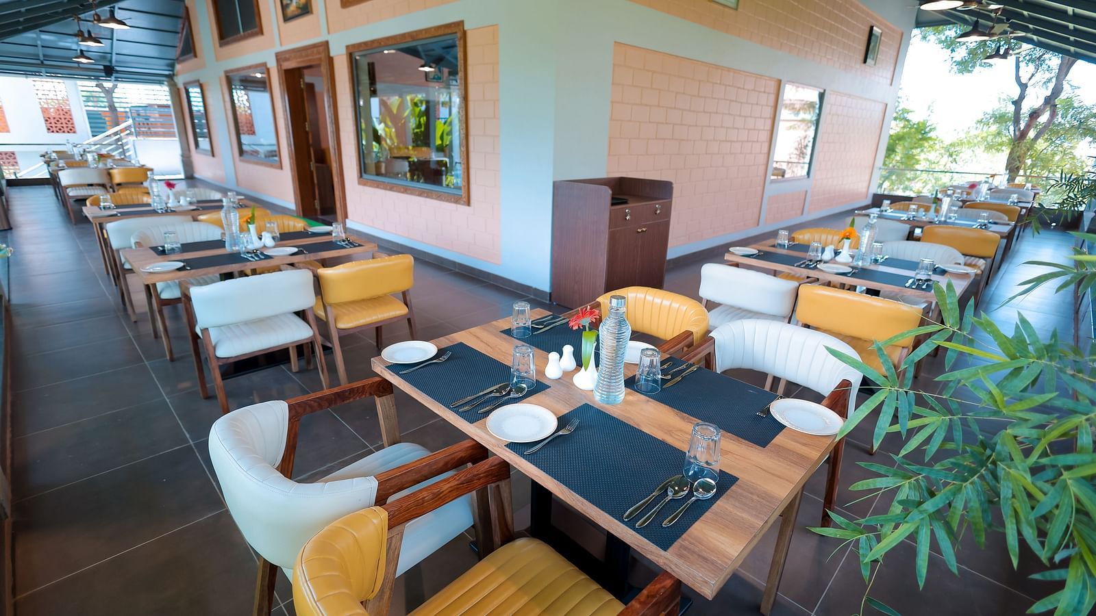 Modern indoor dining space with table settings and greenery at Trishvam Symphony, Krishnagiri.