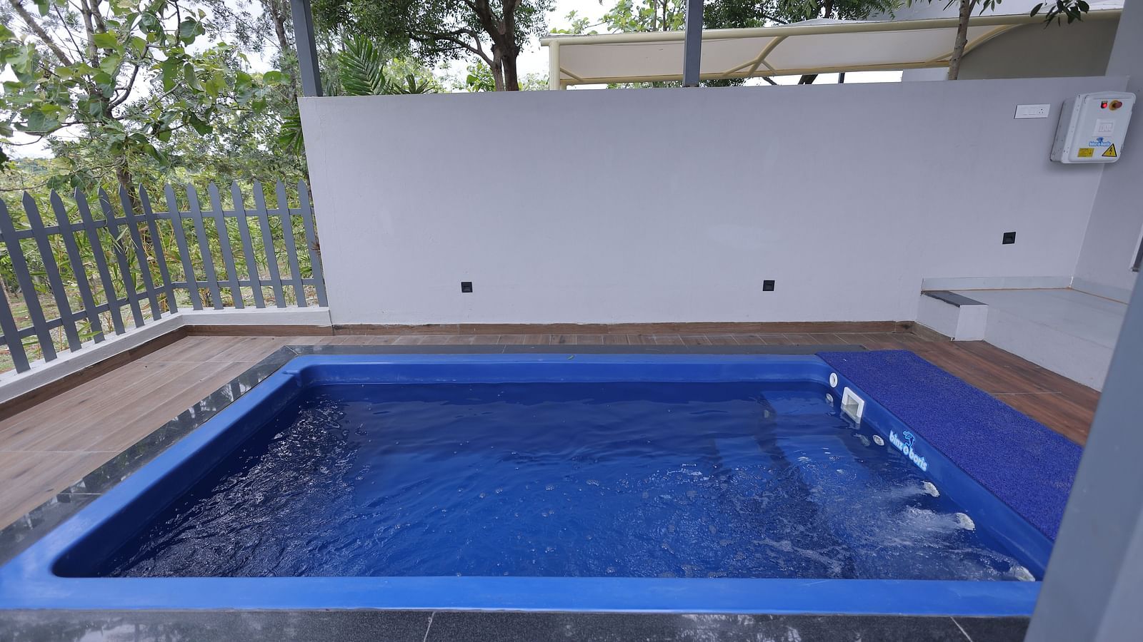 Outdoor private swimming pool bordered by fencing and greenery at Trishvam Symphony, Krishnagiri.