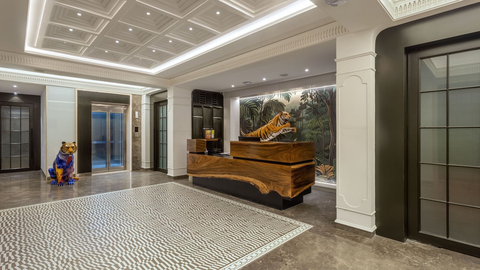Elegant reception at Zibe Luxe Hyderabad by GRT Hotels with forest-inspired wall art, natural wood finishes, and stylish tiled flooring.