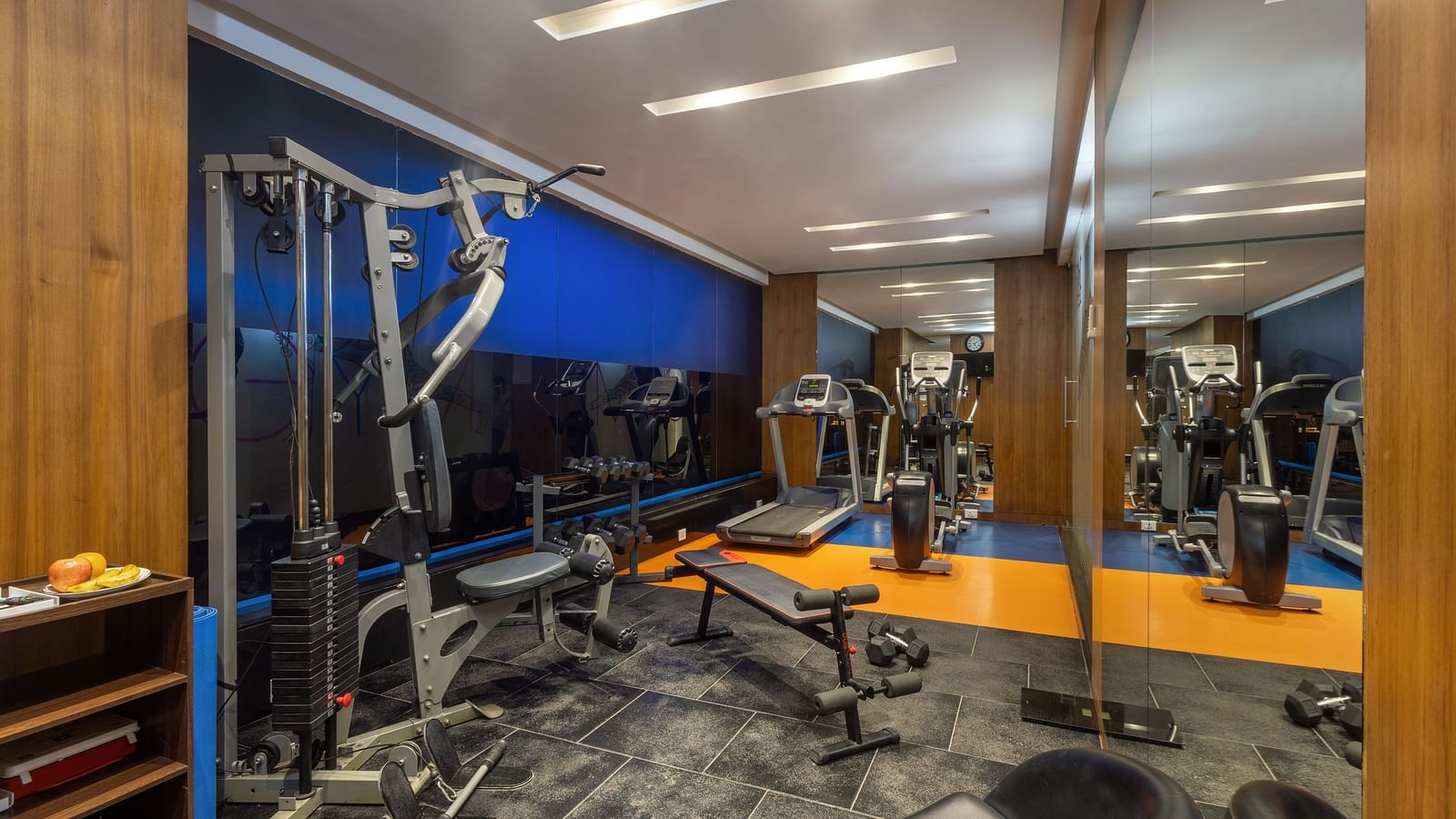 Modern gym at Zibe Luxe Hyderabad by GRT Hotels equipped with cardio machines, multi-gym equipment, and full-wall mirrors.