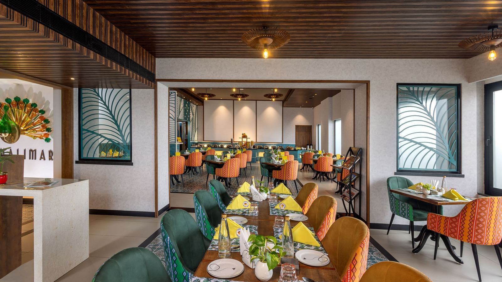 Dining space at Shalimar Restaurant in Zibe Luxe Hyderabad by GRT Hotels, adorned with colorful seating, ceiling lights, and artistic decor.