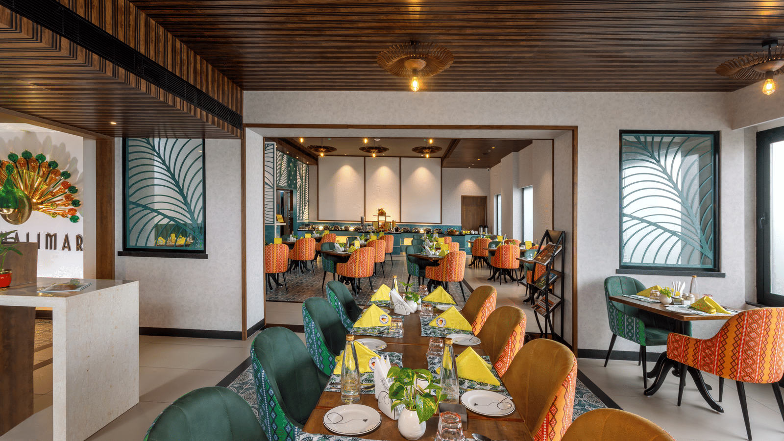 Dining space at Shalimar Restaurant in Zibe Luxe Hyderabad by GRT Hotels, offering colourful seating, ceiling lights, artistic decor, and best food in Hyderabad.