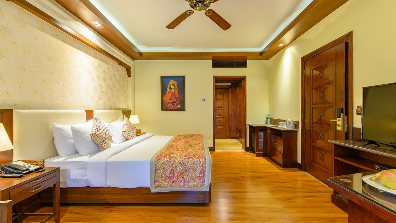 The interiors of our Premium Cottages in Pushkar featuring a balcony, a comfotable bed, sofa chairs 163