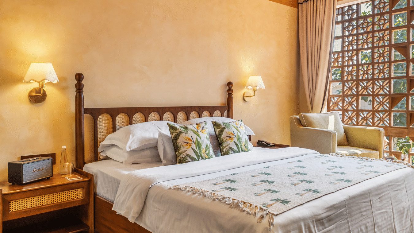 Bedroom at Unseen Boutique Hotel with lattice wooden panels, warm wall tones, bedside tables, and natural light through large windows.