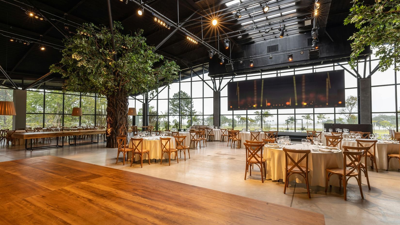 view of a banquet hall with wooden flooring and a tree in the middle