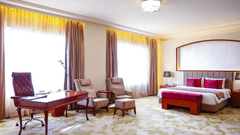 A luxurious bedroom with a king size bed, a work desk, and comfortable seating, bathed in natural light - Balaji Sarovar Premiere, Solapur