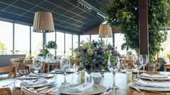 A banquet hall table adorned with flowers and a complete cutlery set.
