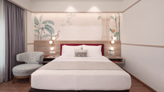 A hotel bedroom with a bed, a seating area, and a TV.