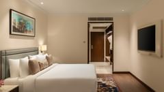 A hotel room at Sarovar Portico, Hanumangarh, with a double bed, a television, a framed painting.