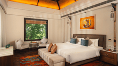 A hotel bedroom with a large bed, seating area by the window, and warm lighting.