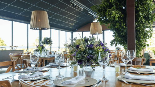 A banquet hall table adorned with flowers and a complete cutlery set.