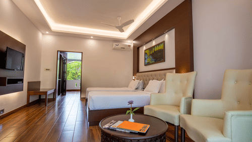 A spacious living room with cream-coloured sofas, a coffee table, wooden flooring, and a TV on the wall, creating a relaxing atmosphere - Black Thunder, Coimbatore