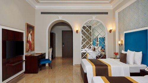 twin beds, a television, and a painting over a table in the PREMIER ROOM - Royal Kingdom Sarovar Portico, Pilibhit