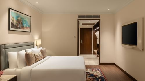 A hotel room at Sarovar Portico, Hanumangarh, with a double bed, a television, a framed painting.